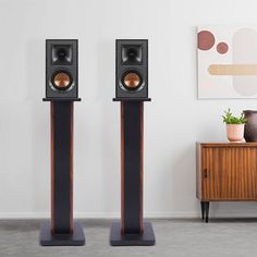 two speakers sitting next to each other on top of a wooden stand in front of a white wall