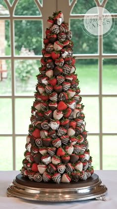 a tower of chocolate covered strawberries on top of a table next to a window