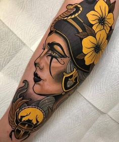 a woman's face with flowers in her hair and an egyptian mask on her arm