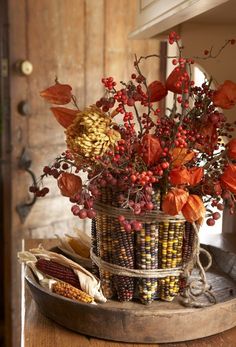 a basket filled with corn and flowers on top of a table