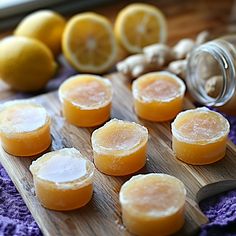 lemons and ginger are on a cutting board next to some jars with orange juice