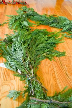 a bunch of green branches laying on top of a wooden floor