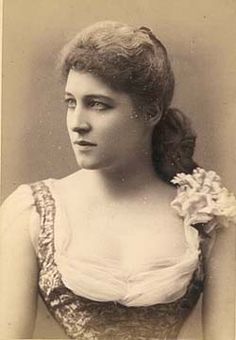 an old photo of a woman with a flower in her hair and wearing a dress