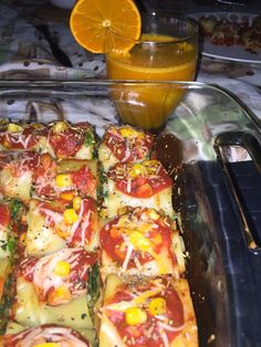 a pizza with tomatoes, cheese and asparagus on it next to a glass of orange juice