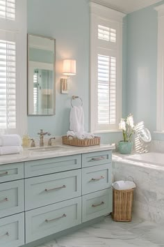 a bathroom with blue walls and white counter tops, along with a large bathtub