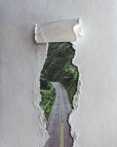 a torn piece of paper with an image of a road going through the hole in it