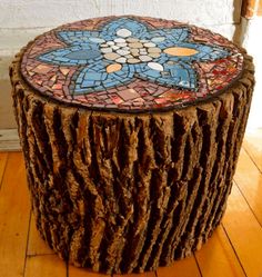 a tree stump with a stained glass flower design on it's top sitting on a wooden floor