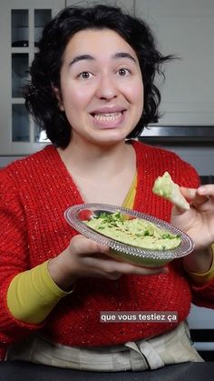 a woman holding a plate with guacamole on it and smiling at the camera