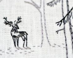 an embroidered deer in the woods with trees