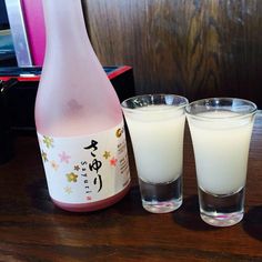 two glasses and a bottle sitting on a table next to each other with liquid in them