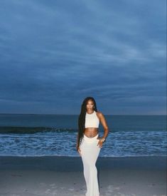 a woman standing on top of a beach next to the ocean