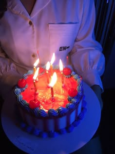 a person holding a cake with lit candles