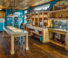 a kitchen with blue walls and wooden floors has an island in the middle that is built into the ceiling