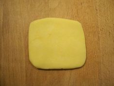 a square shaped piece of cheese sitting on top of a wooden table