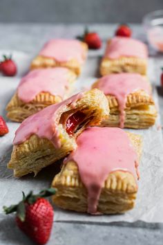 strawberry hand pies with pink icing and strawberries on the side, ready to be eaten