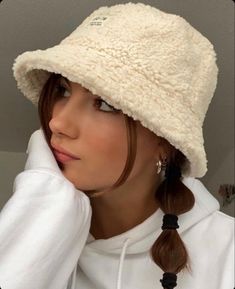 a woman wearing a white hat with braids on her hair and looking off to the side