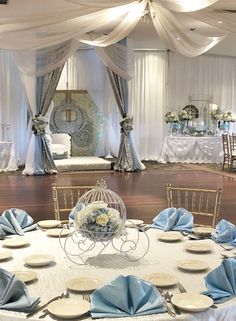 a banquet hall set up with blue and white table cloths, place settings and centerpieces