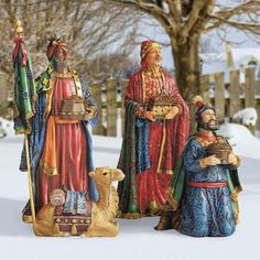 three figurines are standing in the snow with a dog next to them and one is holding a bell