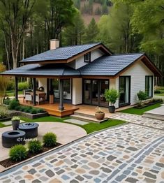 a small white house with a blue roof in the middle of a yard and trees