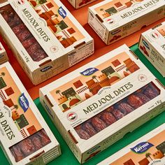 several boxes of medjol dates sitting on a green tablecloth with orange background