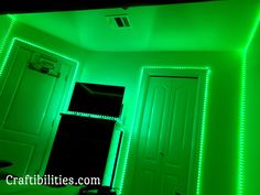 a room with green lights on the ceiling and door to another room in the background