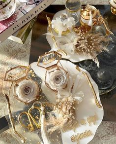 two white plates with gold accents and flowers on them are sitting on a table next to other decorative items