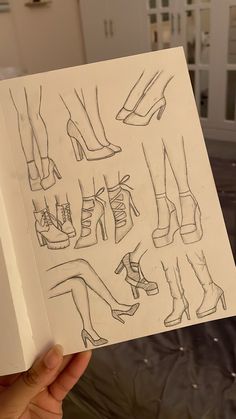 a hand holding up a book with drawings of shoes and heels on the front cover