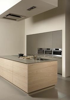 a modern kitchen with an island and stainless steel appliances in the center, along with white walls