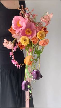 a woman holding a bouquet of flowers in front of her face and wearing a black dress