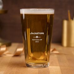 a glass of beer sitting on top of a wooden table