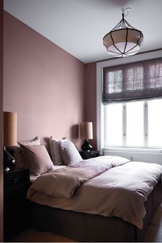 a bed sitting under a window next to a lamp