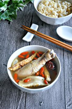 a bowl filled with meat and vegetables next to chopsticks on a wooden table