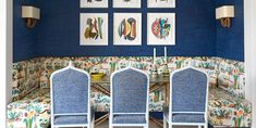 three blue chairs sitting in front of a table with pictures on the wall