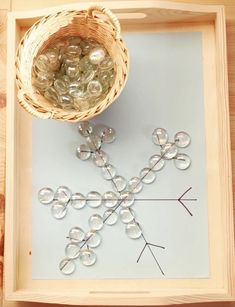 a snowflake made out of glass sitting on top of a wooden tray next to a basket