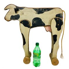 a wooden cow with a bottle in front of it and a string attached to the back