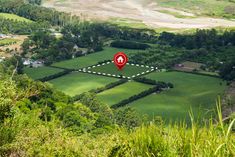 an aerial view of a lush green field with a red marker in the middle that indicates where to go