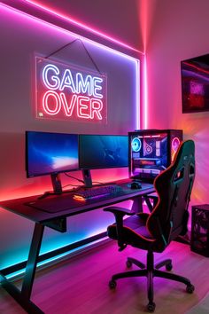 a computer desk with two monitors and a keyboard on it in front of a neon sign that reads game over