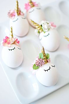 white eggs decorated with unicorn faces and flowers on a tray for desserts or as decorations