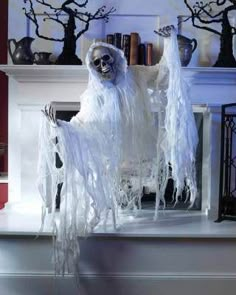 a fake ghost sitting on top of a mantle next to a book shelf filled with books