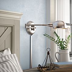 a table with a lamp and some books on it next to a vase filled with plants