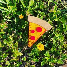 a piece of felt pizza sitting in the grass