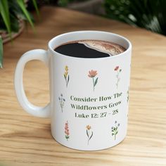 a coffee mug with the words consider how the wildflowers grow luke 12 27