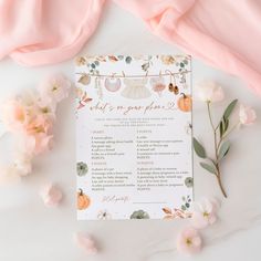 a white wedding ceremony program with peach flowers and greenery on the table next to it