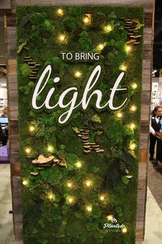 a sign that says to bring light in front of a green wall with lights on it