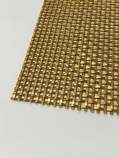 a piece of gold colored metal mesh on a white surface