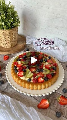 a fruit tart on a table with strawberries and blueberries