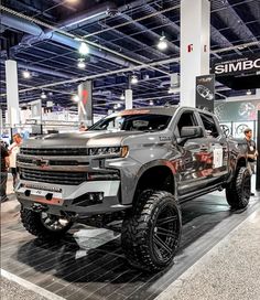 a silver truck is on display at an auto show with people standing around the vehicle