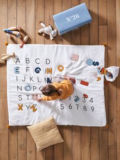 a young child is playing with his toys on the floor in front of a large white banner