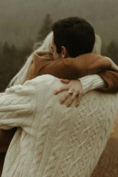 two people hugging each other in front of horses