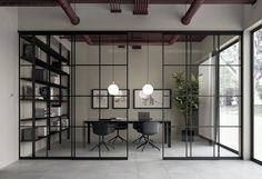 an office with glass partitions and black chairs in front of the desk is surrounded by bookshelves